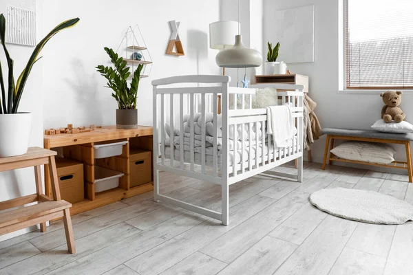 stock image Interior of light children's bedroom with baby crib, table and bench