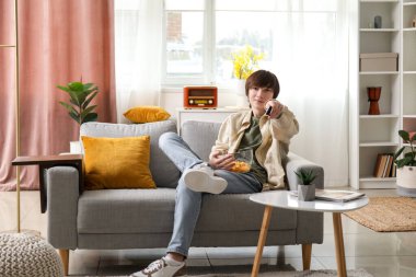 Evde çipli genç bir çocuk televizyon izliyor.