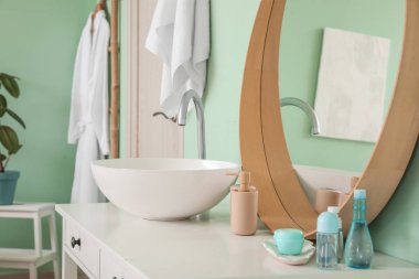 Banyonun içinde seramik lavabo ve banyo aksesuarları aynanın yanında.