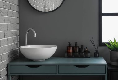 Table with sink and bath accessories in modern bathroom