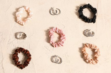 Set of stylish earrings and scrunchies on light background