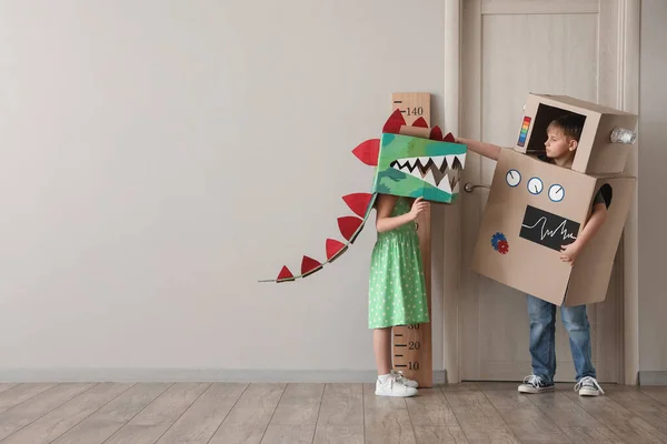 Stock image Little children in cardboard costumes playing near light wall