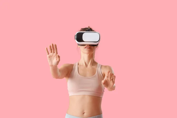 stock image Pretty young woman in VR glasses on pink background