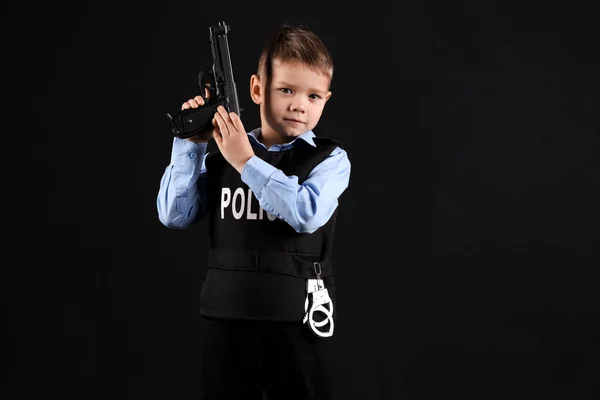 Cute little police officer with gun on black background