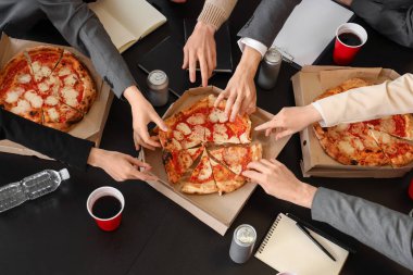 Bir grup iş adamı ofisteki masadan lezzetli pizzaları alıyor.