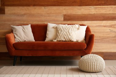 Ahşap duvarın yanındaki rahat kahverengi koltukta şık dekoratif yastıklar.