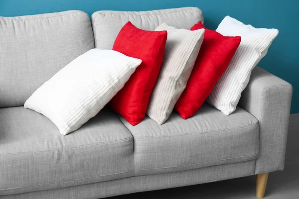 蓝色墙壁附近舒适的灰色沙发上的时髦装饰枕头 — 图库照片
