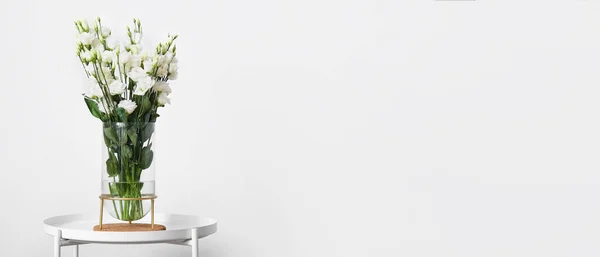 光の壁の近くのテーブルの上に美しいイースタスの花と花瓶 デザインのバナー — ストック写真