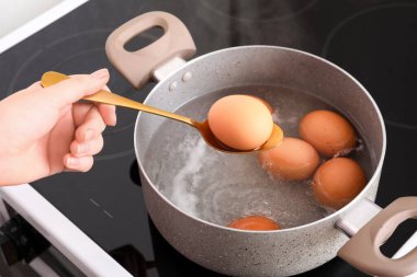 Mutfakta haşlanmış yumurtayla kaşık tutan kadın, yakın plan.