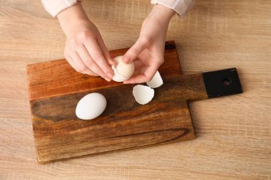 Ahşap masada haşlanmış yumurta soyan kadın, üst manzara.