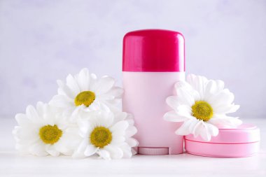 Kozmetik ürünleri ve güzel papatya çiçekleri açık ahşap masada.