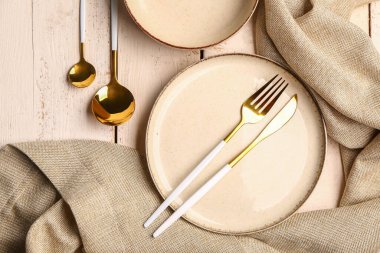 Plate, bowl and set of cutlery on white wooden background