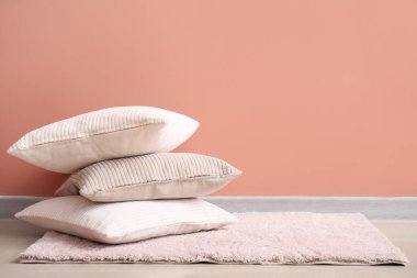 Pembe duvarın yanında şık dekoratif yastıklı yumuşak halı.