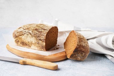 Board with sliced rye bread on grey background