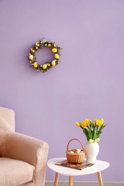 Interior of living room with Easter wreath, armchair and table