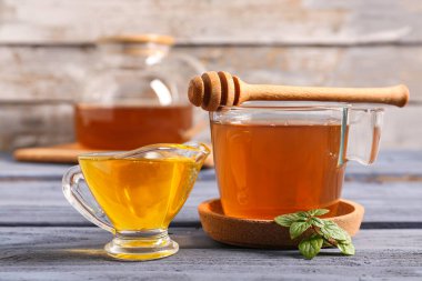 Bir fincan yeşil çay ve ahşap masadaki ballı sos teknesi.