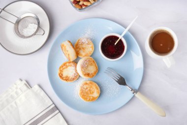 Lezzetli süzme peynirli krep, çilekli reçel ve açık arkaplanda bir fincan kahve.