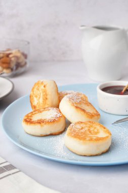 Açık arkaplanda lezzetli süzme peynirli krep ve çilek reçeli tabağı, yakın plan.