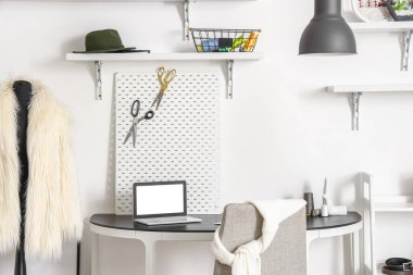 Interior of modern atelier with tailor's workplace, shelves and mannequin