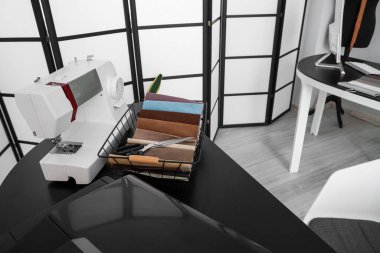 Tailor's workplace with sewing machine and fabric samples in atelier