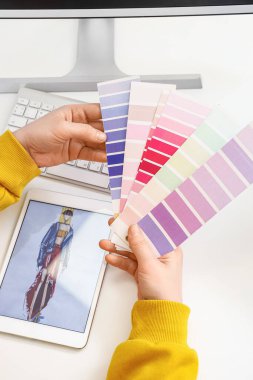 Female tailor with color palettes at table, closeup