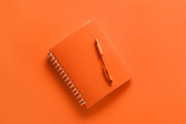 オレンジの背景にペン付きノート — ストック写真