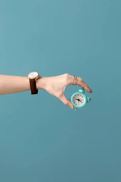 腕時計と青の背景に小さな目覚まし時計を持つ女性 — ストック写真