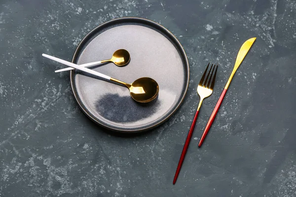 Clean plate and set of cutlery on grey grunge background