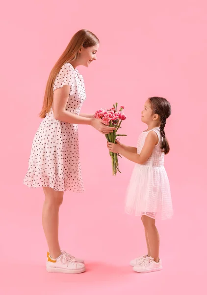Aranyos Kislány Köszönti Anyját Virágokkal Rózsaszín Háttér — Stock Fotó