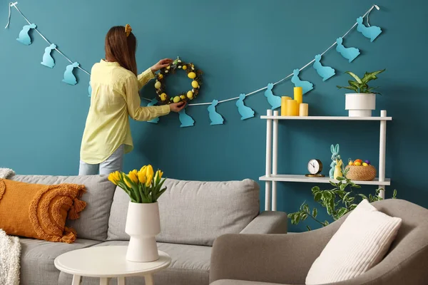 Young Woman Hanging Easter Wreath Blue Wall Living Room — Stok fotoğraf