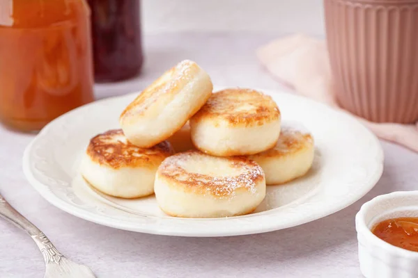 stock image Plate with tasty cottage cheese pancakes on light table, closeup