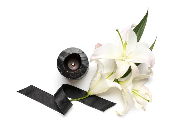 美しいユリの花 黒い葬儀リボンと白い背景に燃えるろうそくと構成 — ストック写真