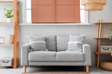 Rahat oturma odasının iç tarafında yastıklar olan gri kanepe.