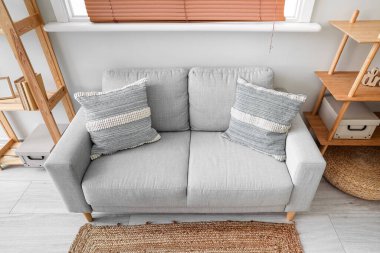 Rahat oturma odasının iç tarafında yastıklar olan gri kanepe.