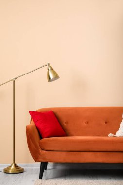 Kahverengi kanepe. Yastık ve lamba bej duvarın yanında.