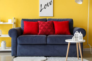 Kırmızı yastıklı, mavi koltuklu oturma odasının içi.