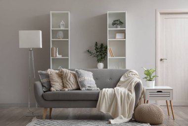 Gri kanepe ve raf üniteleriyle oturma odasının içinde.