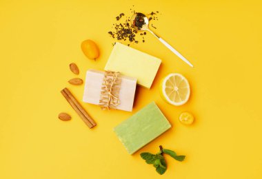 Composition with soap bars and natural ingredients on yellow background