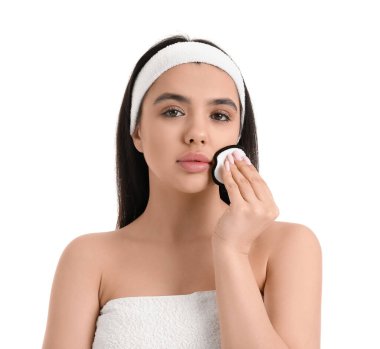 Beyaz arka planda pamuklu ped ile makyajı kaldıran genç kadın, yakın plan.