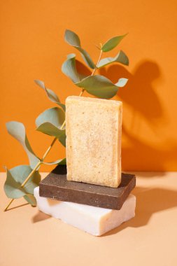 Stack of natural soap bars and eucalyptus branch on color background