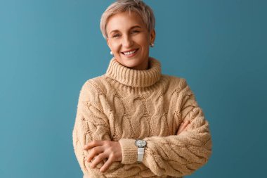 Mavi arka planda bej kazaklı güzel olgun bir kadın.