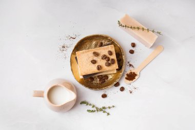 Plate with natural soap bars, coffee beans and milk on light background