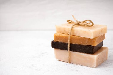 Stack of natural soap bars tied with rope on light background