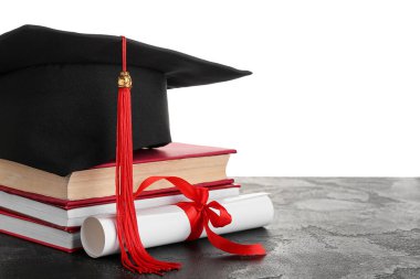 Diplomalı mezuniyet şapkası ve siyah masa üzerine beyaz arka planla ilgili kitaplar.