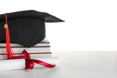 Diplomalı mezuniyet şapkası ve beyaz arka planlı kitaplar.
