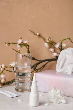 Burun damlaları, haplar, mendiller ve masada bir bardak su. Mevsimsel alerji kavramı