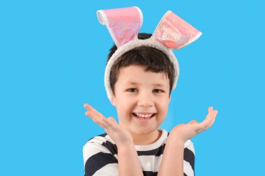 Cute little boy with bunny ears on light blue background