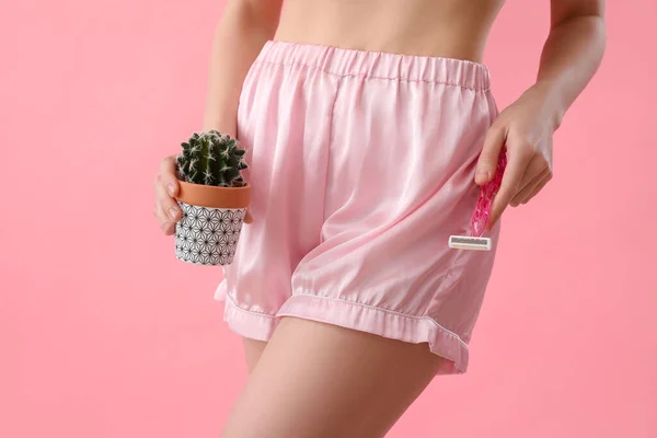 Young woman with razor and cactus on pink background, closeup