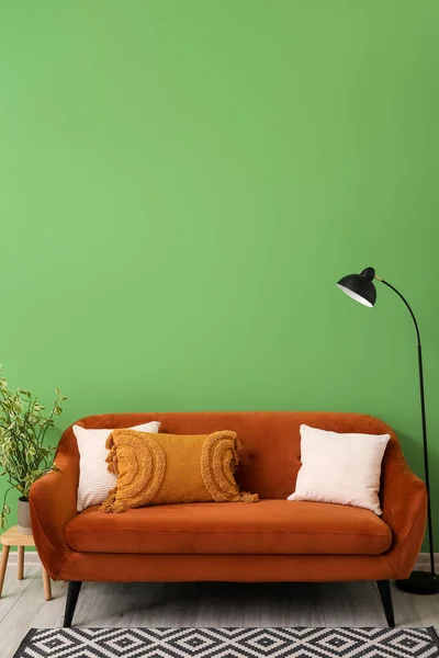 靠近绿墙的褐色沙发 有靠垫 灯具和室内盆栽 — 图库照片