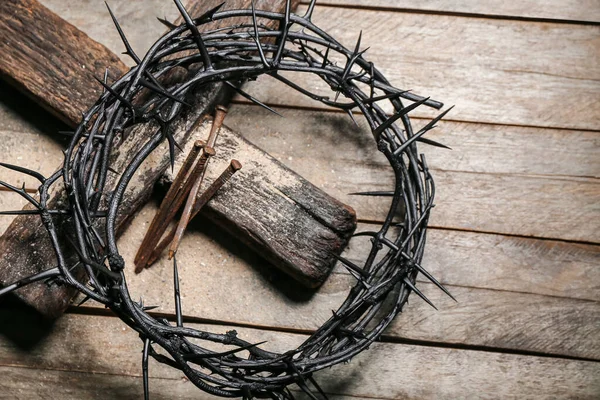 Crown of thorns with nails and cross on wooden background